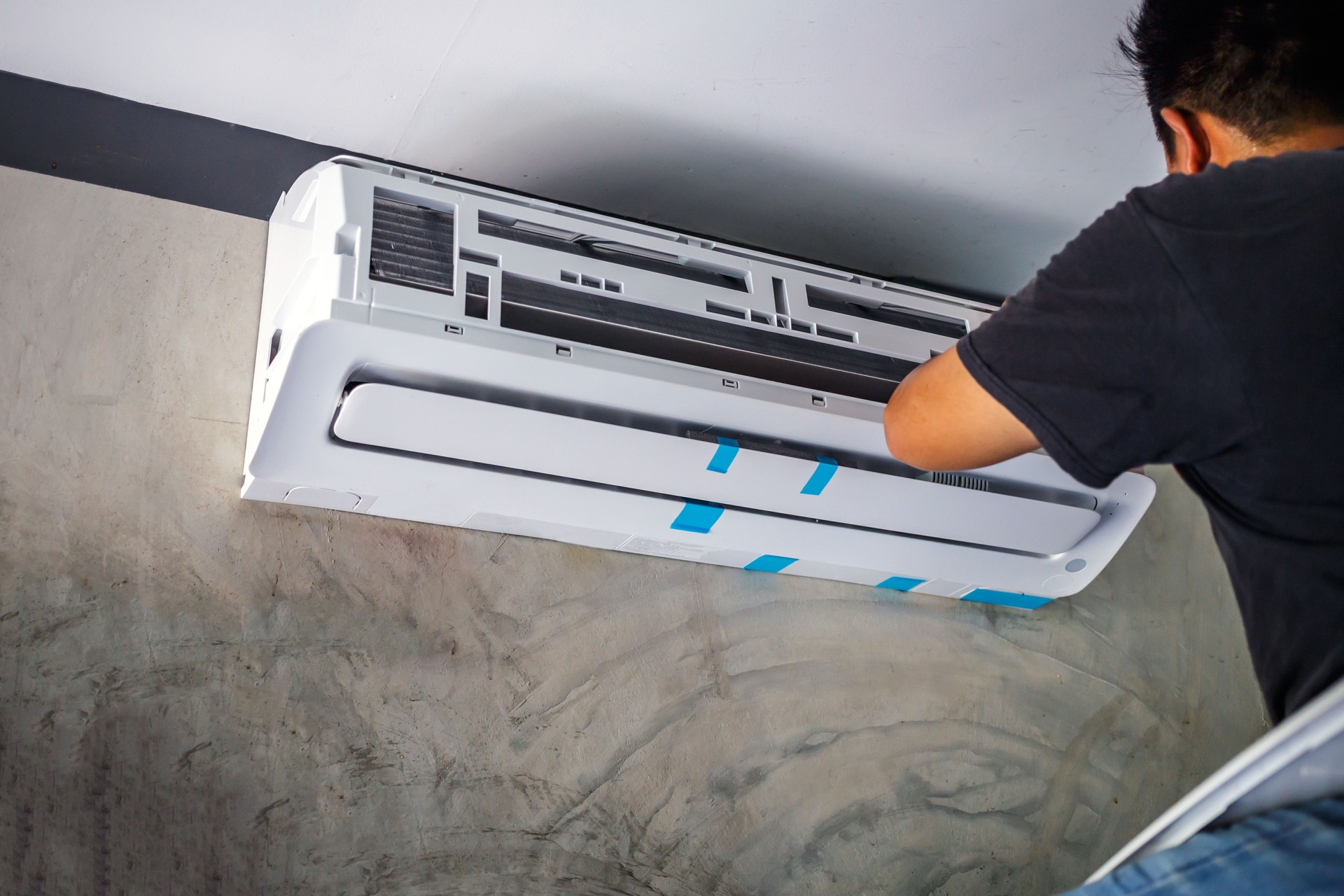 The air conditioner technician installs a new air conditioner in the room.